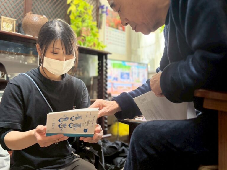 訪問先の居間で、看護師が利用者様に薬の説明をしている