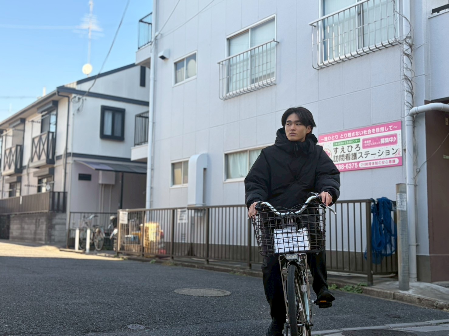 すえひろ訪問看護ステーションの前を自転車で訪問に向かう看護師(足立区の訪問看護師求人)