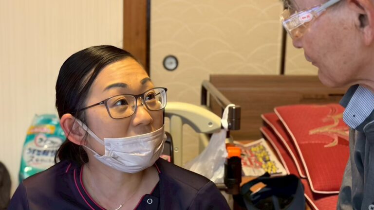 訪問先で利用者様と向き合い、目を合わせて話す看護師・清水